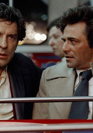 Kolorowe zdjęcie. Dwóch dorosłych mężczyzn siedzi w wagoniku w kolejce w wesołym miasteczku. Rozmawiają.