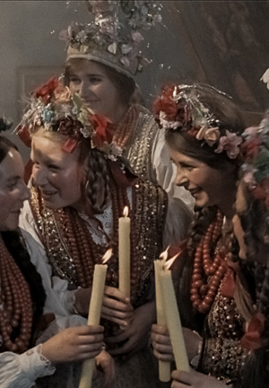 Kolorowy kadr z filmu. Kobiety z innej epoki, zbierają się przed weselem. Na głowach mają wianki, a ich stroje są z innej epoki.