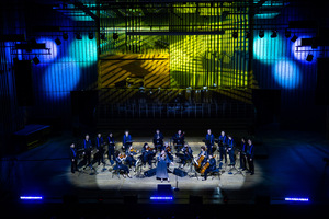 Na estradzie siedzi sześć pań , trzech panów to zespół No-Net. Za nimi stoi męski chór ubrany w czarne spodnie i koszulę oraz niebieskie szelki .Z przodu estrady w niebieskiej sukni solistka. Tło estrady w odcieniach niebieskich i złotych.