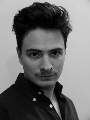 Portret uśmiechniętego mężczyzny w czarnej koszuli.
