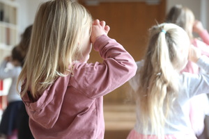 Zdjęcie przedstawiające grupę dziewczynek stojących tyłem. Dłonie przykładają do oczu robiąc z nich okulary.