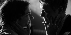 Czarno-biały kadr z filmu. Kobieta i mężczyzna, młodzi dorośli. Patrzą na siebie z uczuciem, trzymają dłonie na twarzach drugiej osoby.