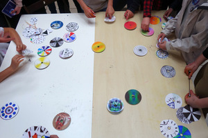 Zdjęcie rąk dzieci. Widać z góry stół i kolorowe kółka.