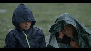 Kadr z filmu. Dwoje dzieci ubranych w peleryny przeciwdeszczowe.