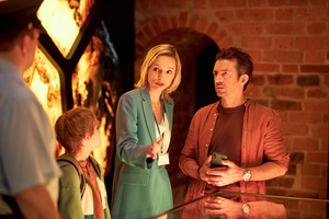 Kadr z filmu. Trzy dorosłe osoby rozmawiają ze sobą, pomiędzy nimi stoi dziecko.