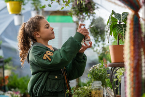 Kadr z filmu. Dziewczyna spryskuje wodą roślinkę w doniczce.