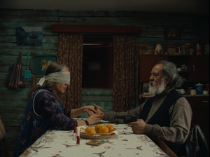 Kadr z filmu. Kobieta i mężczyzna siedzą przy stole. Kobieta ma zasłonięte oczy przepaską.