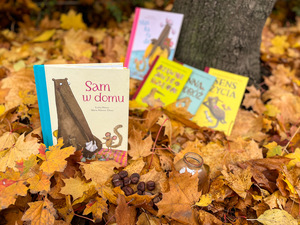 Książki dla dzieci leżą na jesiennych liściach.