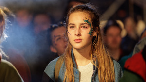 Kadr z filmu. Dziewczyna wśród tłumu. Dziewczyna ma brokat na twarzy.