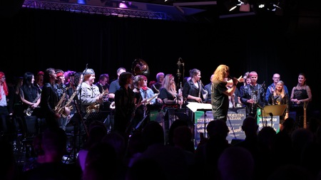 Artyści Chóru Męskiego stojący na scenie na sali widowiskowej podczas koncertu