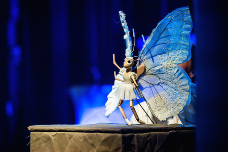 Grafika przedstawia lalkę motyla w kolorze białym, animowaną przez aktorkę.