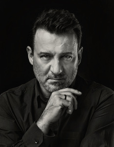 Czarno-biały portret zamyślonego mężczyzny.