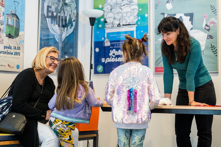 Zdjęcie przedstawia dorosłych oraz dzieci. Rozmawiają i uśmiechają się.