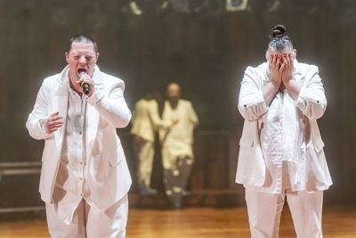 Dwoje aktorów na scenie ubranych na biało.