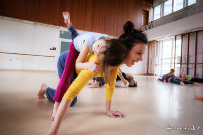 Kobieta ćwiczy z dzieckiem, które leży na jej plecach.