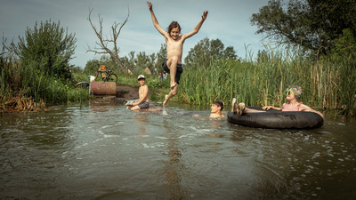 Kadr z filmu. Młodzież bawi się w wodzie. Jeden z chłopców wskakuje do wody.