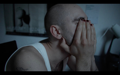 Kadr z filmu. Mężczyzna zakrywający twarz rękami.