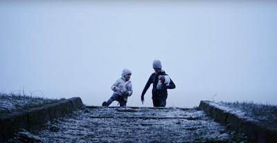 Kadr z filmu. W oddali widać dwójkę dzieci, które idą na spacer.