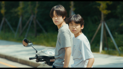 Kadr z filmu. Dwóch chłopców siedzących na skuterze.