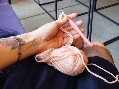 zdjęcie przedstawia dłoń w której jest szydełko obok leży włóczka