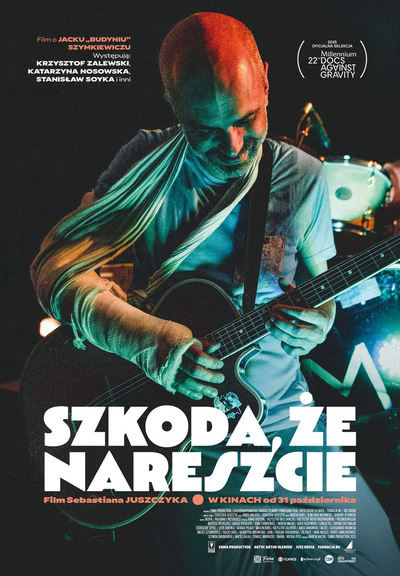W centrum plakatu łysy mężczyzna z zabandażowaną ręką grający na gitarze. Na dole biały napis z tytułem filmu.