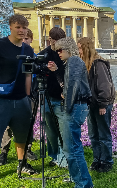 Grupa młodzieży stoi za kamerą.